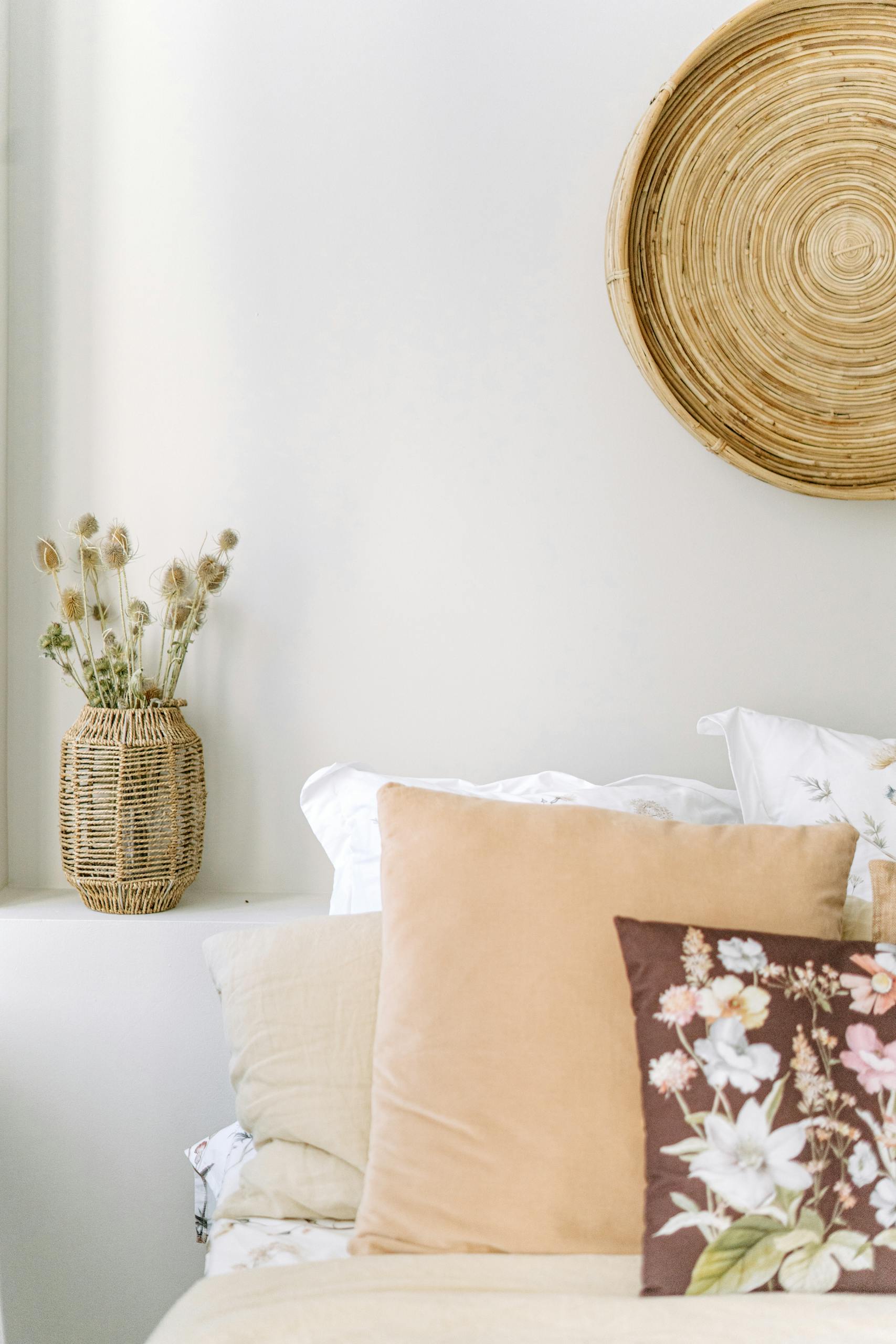A minimalist bedroom featuring neutral tones, textured textiles, and floral accents for a cozy vibe.